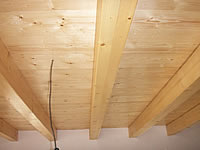 Pohled na stropní trámy z KVH, na nich je dřevěná podlaha oboustranně pohledová, ze shora pochůzná a ze spodu pohledová jako palubkový obklad. Rozteč  mezi trámy je 80 cm a tl. podlahy je 27 mm × 146 mm × 4 m oboustranně pohledová.